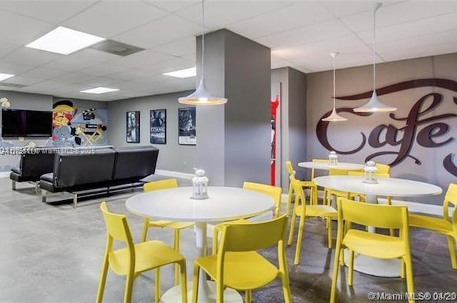 dining area featuring a drop ceiling and baseboards