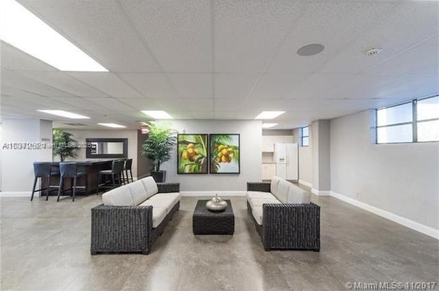 living room featuring baseboards and a drop ceiling