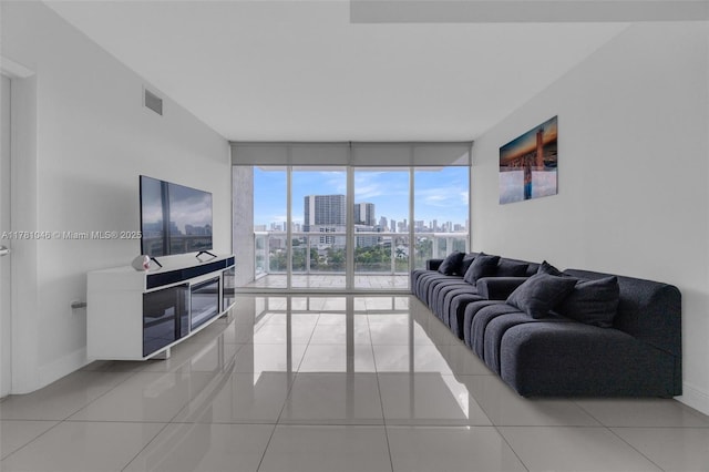 living room featuring visible vents, baseboards, floor to ceiling windows, and tile patterned flooring