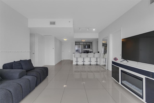 living area with track lighting, visible vents, baseboards, and light tile patterned floors