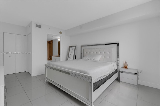 bedroom with ensuite bath, visible vents, baseboards, and light tile patterned floors