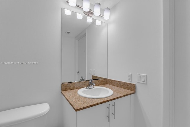 bathroom with toilet, vanity, and visible vents