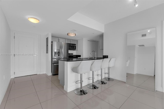 kitchen featuring dark countertops, a breakfast bar, a peninsula, appliances with stainless steel finishes, and visible vents