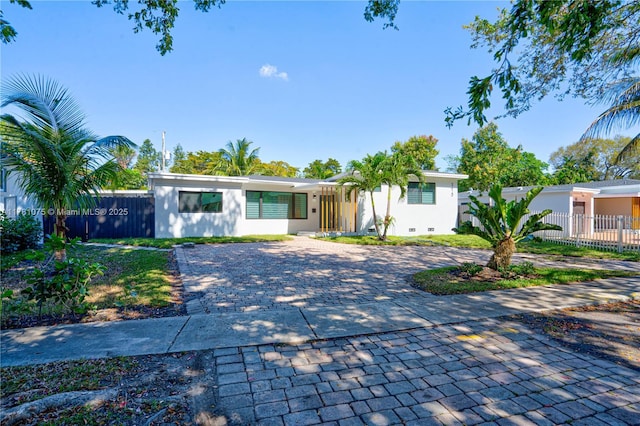 ranch-style home featuring fence, stucco siding, and decorative driveway
