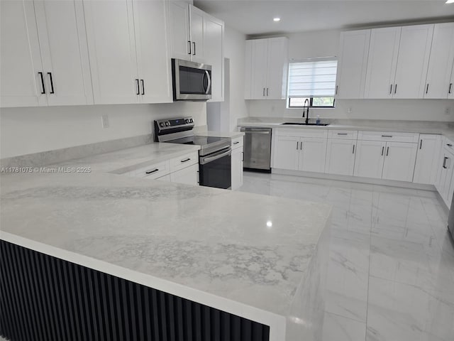 kitchen with light stone countertops, appliances with stainless steel finishes, marble finish floor, white cabinets, and a sink