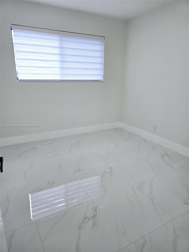 unfurnished room with a healthy amount of sunlight, marble finish floor, and baseboards