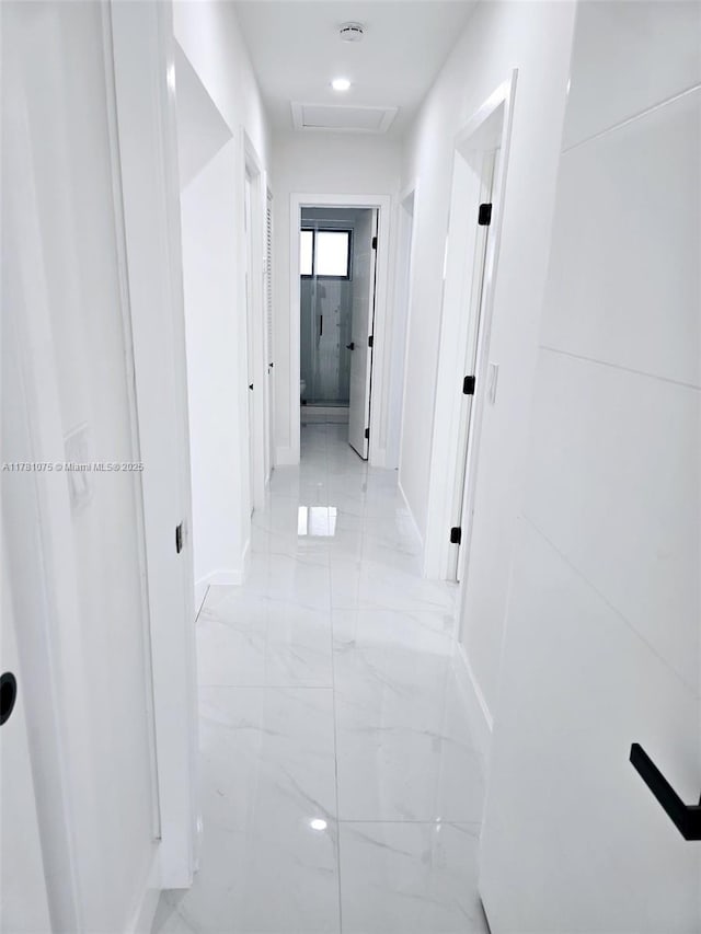 corridor with baseboards, attic access, and marble finish floor