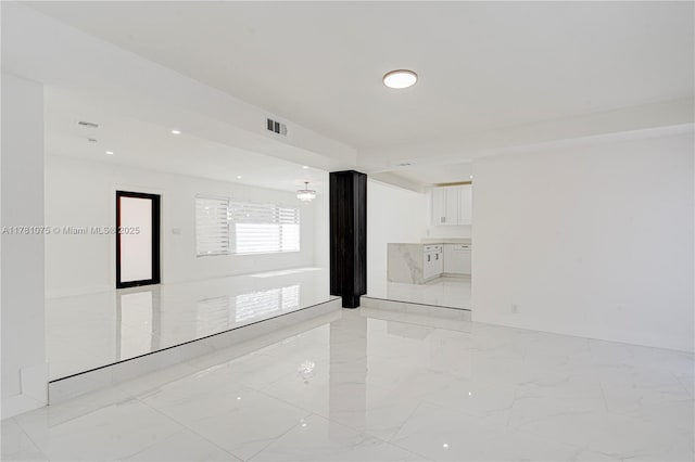 spare room featuring marble finish floor and visible vents