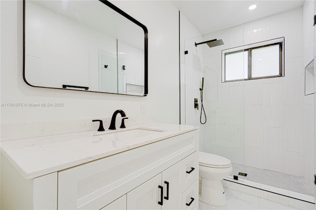 bathroom with vanity, toilet, marble finish floor, and tiled shower