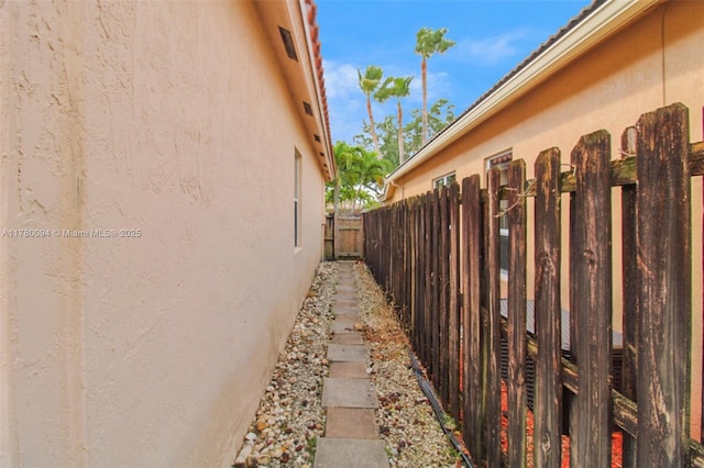 view of side of home featuring fence and stucco siding