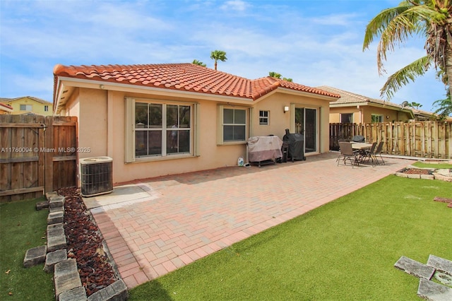 rear view of property featuring central AC unit, stucco siding, fence, and a tile roof