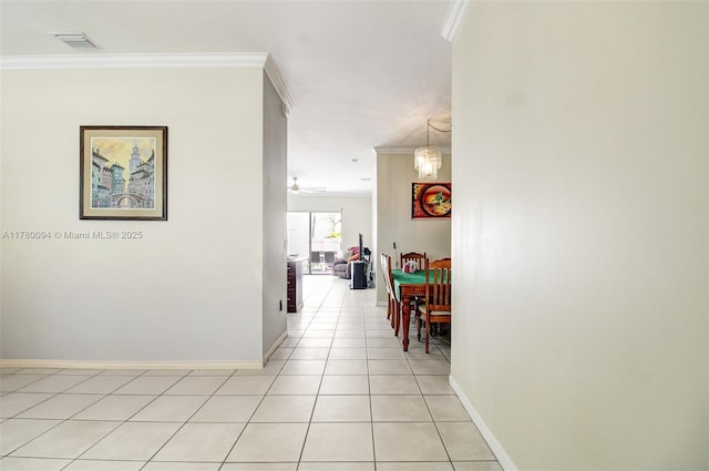 hallway with crown molding, light tile patterned floors, and baseboards