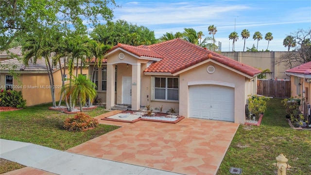 mediterranean / spanish-style house featuring stucco siding, an attached garage, a front yard, a tile roof, and fence