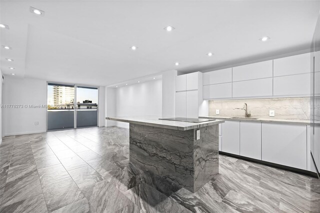 1658 Bay Rd Unit 504, Miami Beach, FL 33139 - kitchen with marble finish floor, modern cabinets, black electric stovetop, and white cabinetry