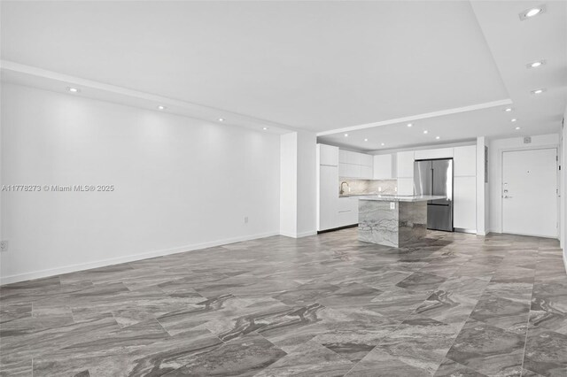 1658 Bay Rd Unit 504, Miami Beach, FL 33139 - unfurnished living room featuring a tray ceiling, marble finish floor, baseboards, and recessed lighting