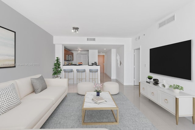 living area featuring visible vents, baseboards, and light tile patterned flooring