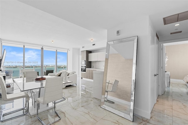 dining space featuring baseboards, visible vents, a water view, and marble finish floor