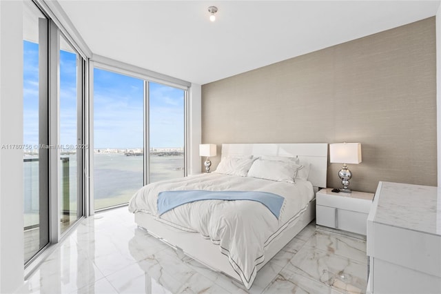 bedroom with access to exterior, a wall of windows, a water view, and marble finish floor