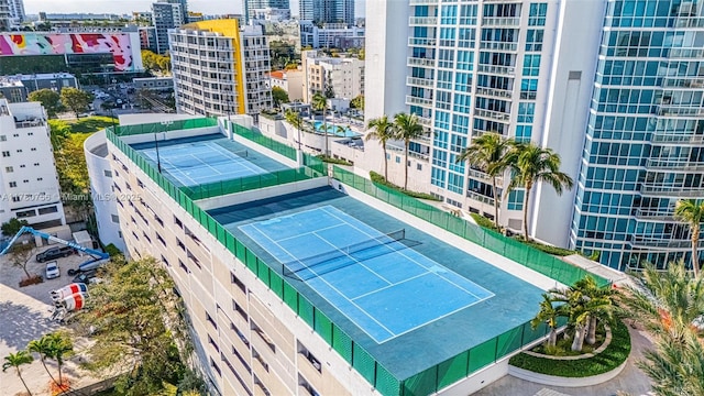 view of tennis court featuring a city view and fence