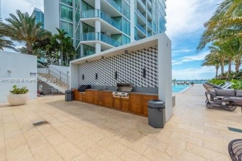 view of patio with a beach view, area for grilling, and a water view
