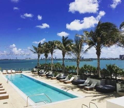 pool featuring a patio and a water view