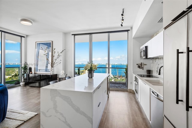 3470 E Coast Ave Unit H2601, Miami, FL 33137 - kitchen featuring stainless steel appliances, a kitchen island, floor to ceiling windows, a water view, and white cabinets