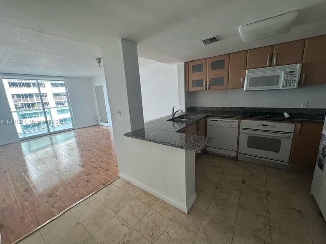 2101 Brickell Ave Unit 502, Miami, FL 33129 - kitchen with white appliances, glass insert cabinets, a peninsula, open floor plan, and dark stone countertops