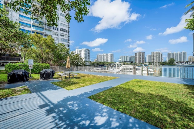 view of community featuring a view of city, fence, and a lawn