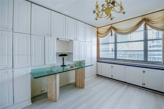 unfurnished office with an inviting chandelier, light wood-style floors, and a textured ceiling
