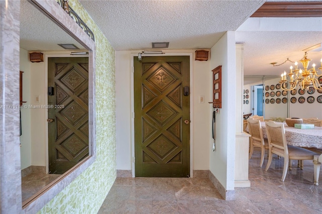 foyer entrance with an inviting chandelier, a textured ceiling, and baseboards