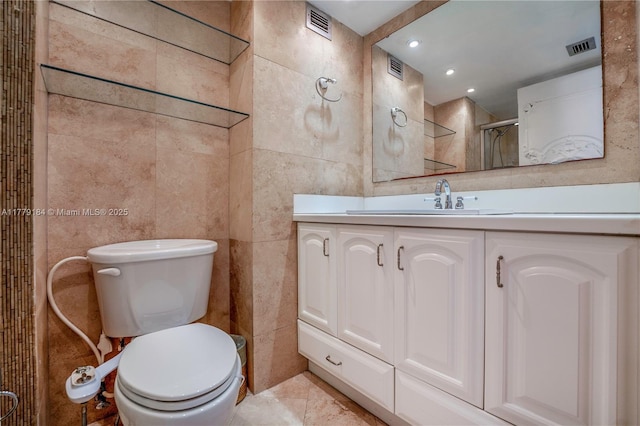 bathroom with toilet, tile walls, visible vents, and vanity