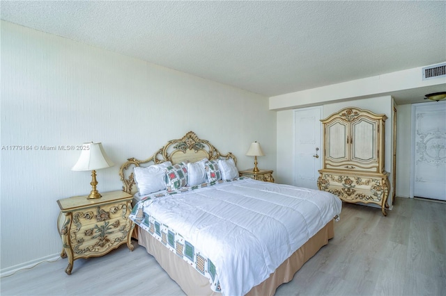bedroom with a textured ceiling, visible vents, and light wood-style flooring
