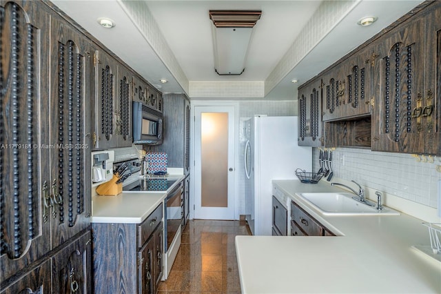 kitchen with a sink, black microwave, granite finish floor, dark brown cabinetry, and electric range oven