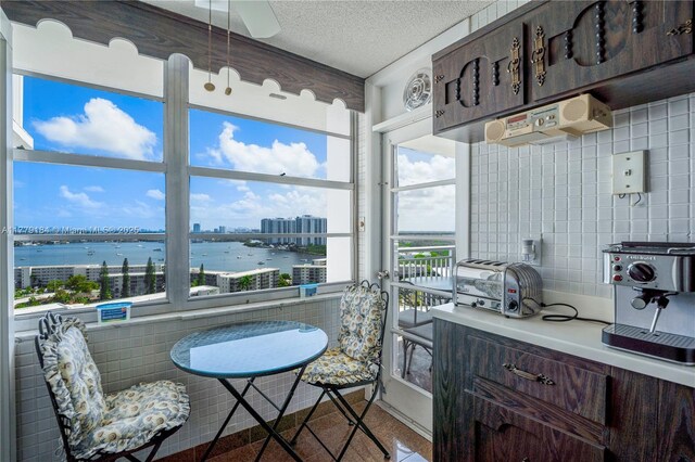 kitchen with a water view, tasteful backsplash, dark brown cabinetry, light countertops, and a toaster