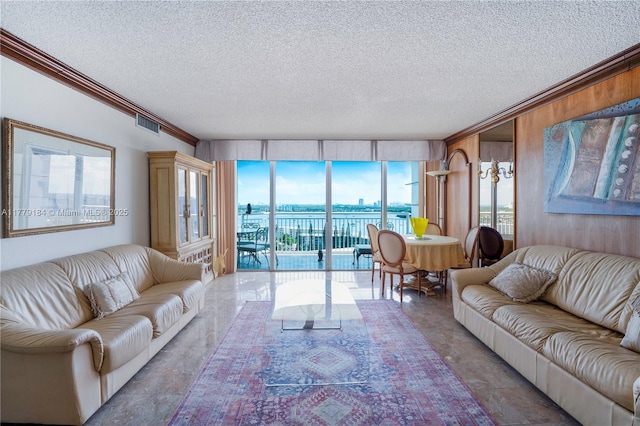 living area with wood walls, a textured ceiling, visible vents, and crown molding