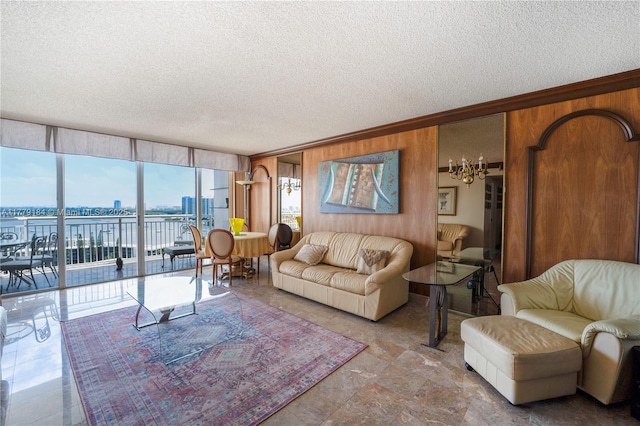 living room featuring a textured ceiling, wooden walls, a chandelier, and a water view