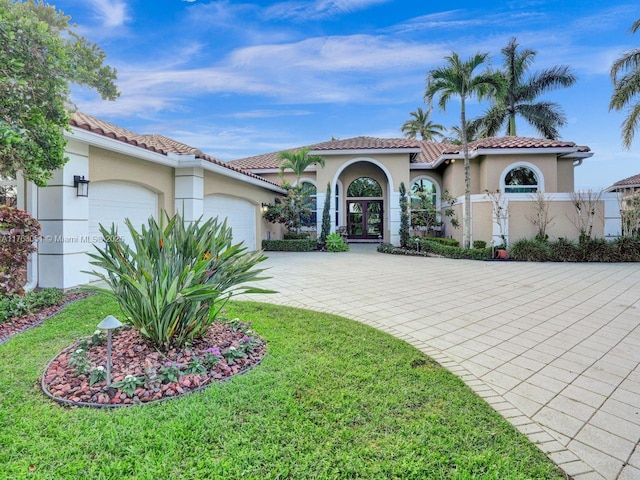 mediterranean / spanish home with stucco siding, driveway, french doors, an attached garage, and a tiled roof