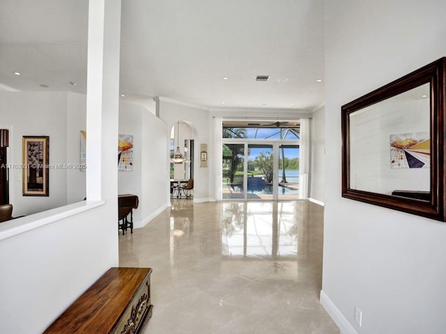 hallway with baseboards, ornamental molding, recessed lighting, visible vents, and arched walkways