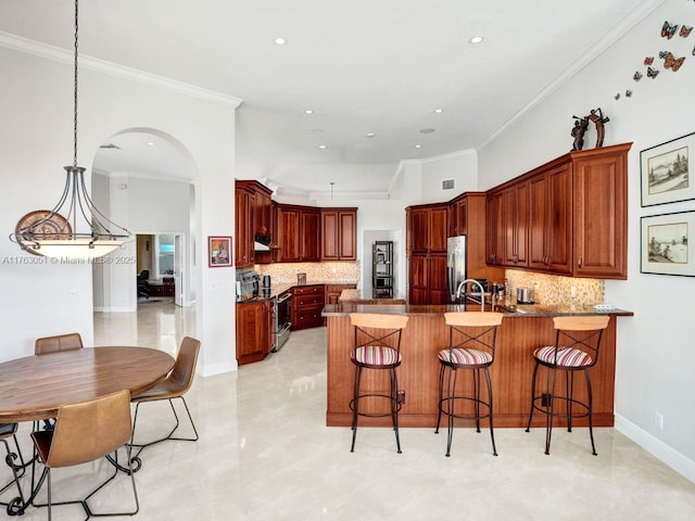 kitchen with backsplash, arched walkways, a peninsula, and stainless steel appliances