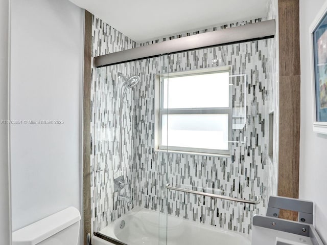 full bathroom with bath / shower combo with glass door and toilet
