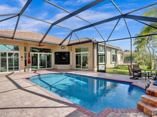 outdoor pool with a lanai, a patio area, and ceiling fan