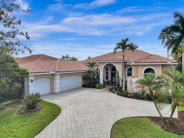 mediterranean / spanish home featuring stucco siding, decorative driveway, an attached garage, and a tile roof