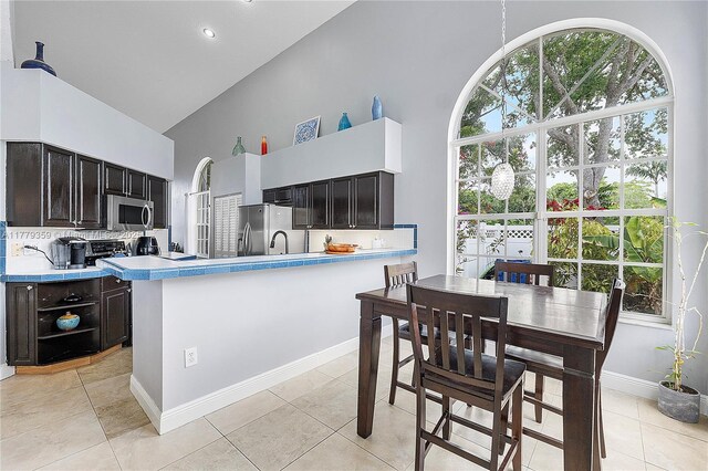 1008 NW 116th Ave, Coral Springs, FL 33071 - kitchen with high vaulted ceiling, appliances with stainless steel finishes, light countertops, decorative backsplash, and a peninsula