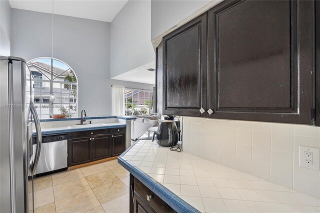 1008 NW 116th Ave, Coral Springs, FL 33071 - kitchen with stainless steel appliances, tile counters, dark brown cabinets, light tile patterned floors, and decorative backsplash
