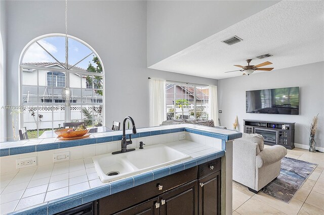 1008 NW 116th Ave, Coral Springs, FL 33071 - kitchen with tile counters, dark brown cabinetry, light tile patterned floors, open floor plan, and ceiling fan