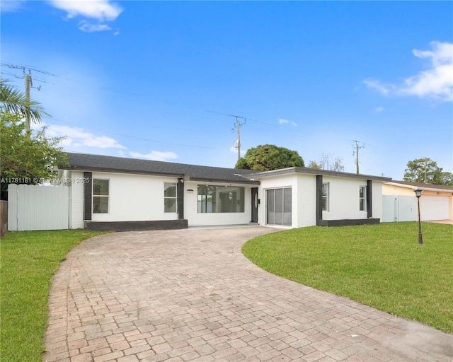 view of front of property featuring a front lawn, fence, an attached garage, and decorative driveway