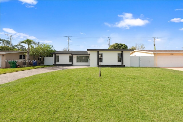 view of front of house featuring driveway, stucco siding, fence, and a front lawn