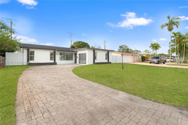 ranch-style home with stucco siding, decorative driveway, a front yard, fence, and a garage