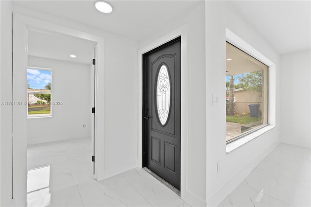 entryway featuring baseboards, recessed lighting, marble finish floor, and a healthy amount of sunlight