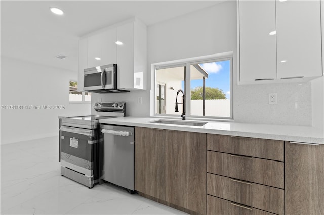 kitchen with white cabinets, modern cabinets, stainless steel appliances, marble finish floor, and a sink